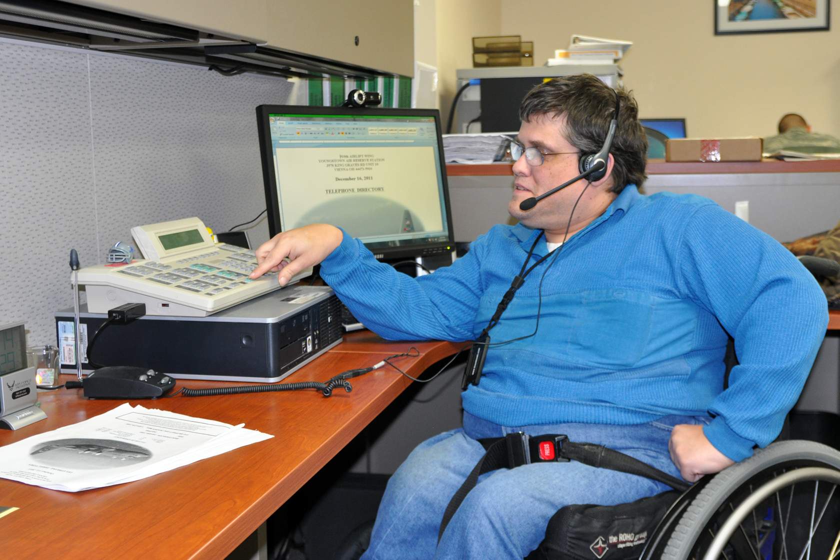 Man in wheelchair seated in front of computer